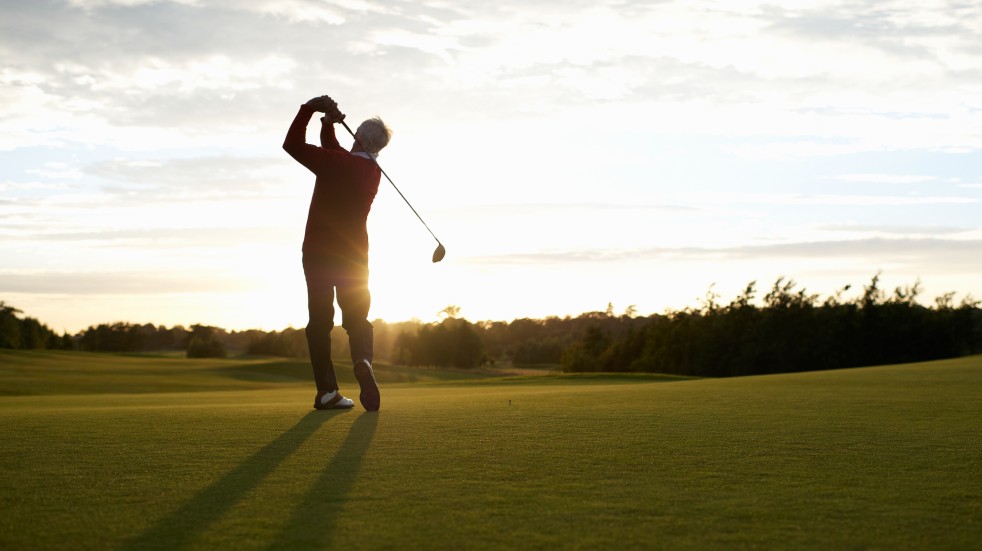 man playing golf at sunset